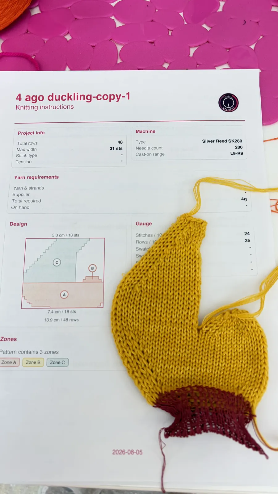Una paperella gialla lavorata a metà, appoggiata su una scheda di istruzioni stampata di xoxkn.it Studio